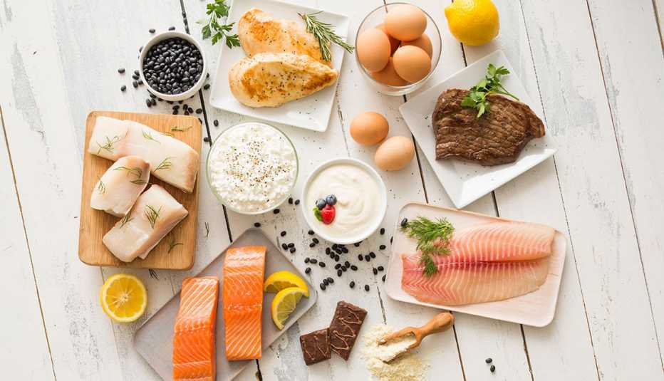 Chicken meat, fish, cottage cheese, yogurt and eggs on white table