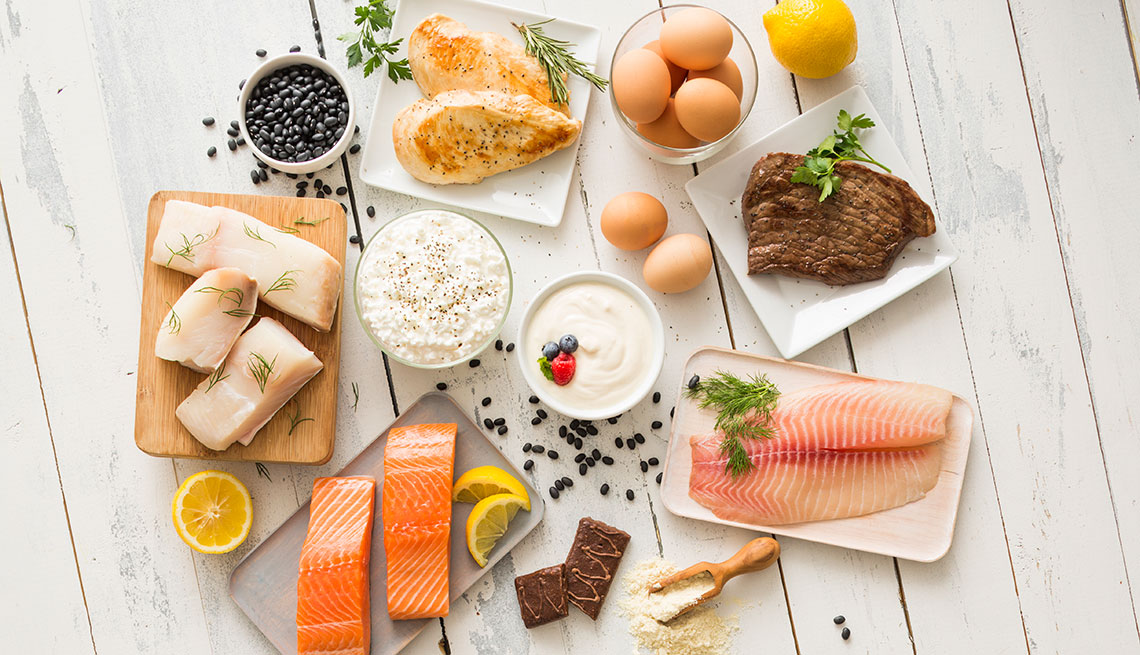 Chicken meat, fish, cottage cheese, yogurt and eggs on white table
