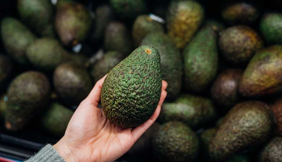 woman holding fresh avocado woman holding fresh avocado