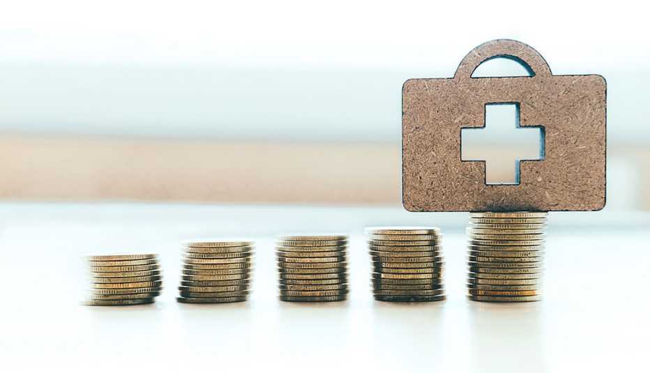 Stacked Coins With First Aid Kit Symbol On Table