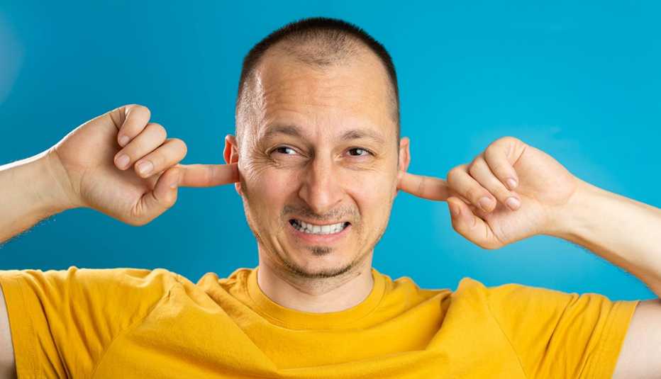 man plugging ears to stop the loud noise