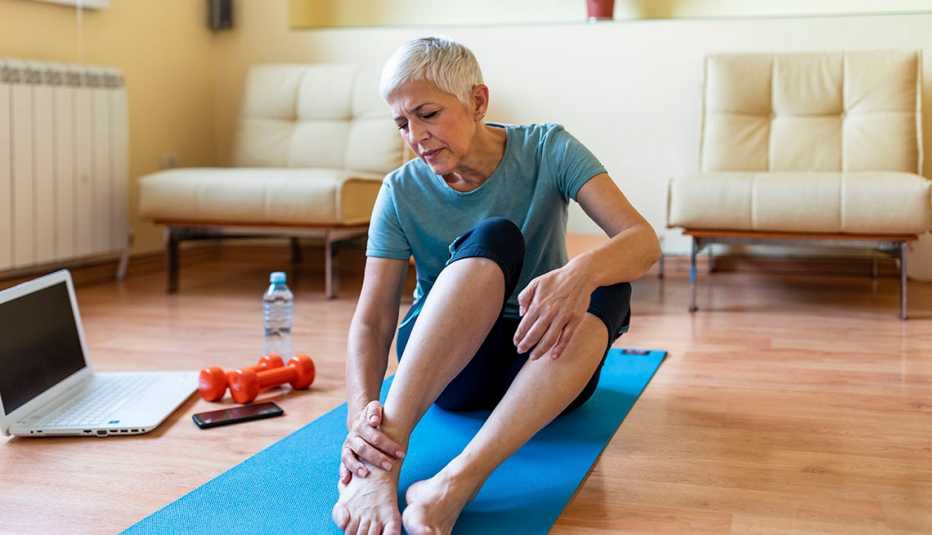 woman seated on the ground rubbing her ankle