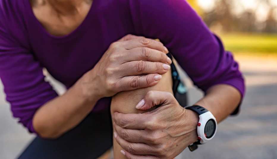 woman holding her injured leg and knee after a run outside