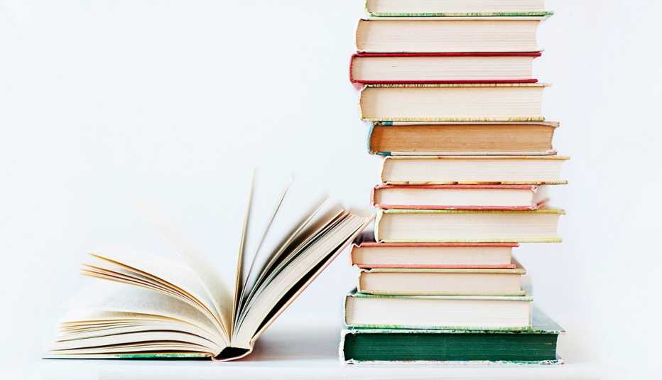 an open book next to a tall stack of unopened books