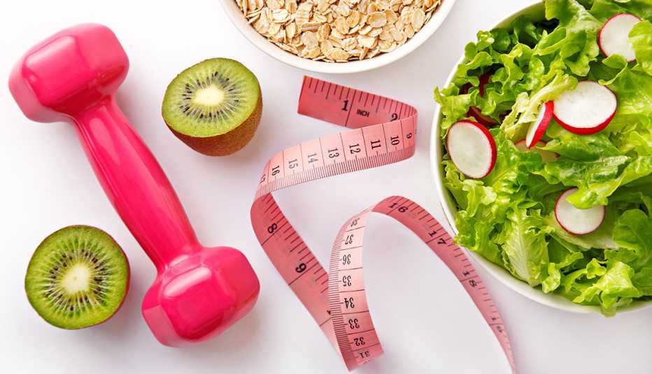 Weight loss imagery, a salad, measuring tape, avocados and a hand weight Weight loss imagery, a salad, measuring tape, avocados and a hand weight