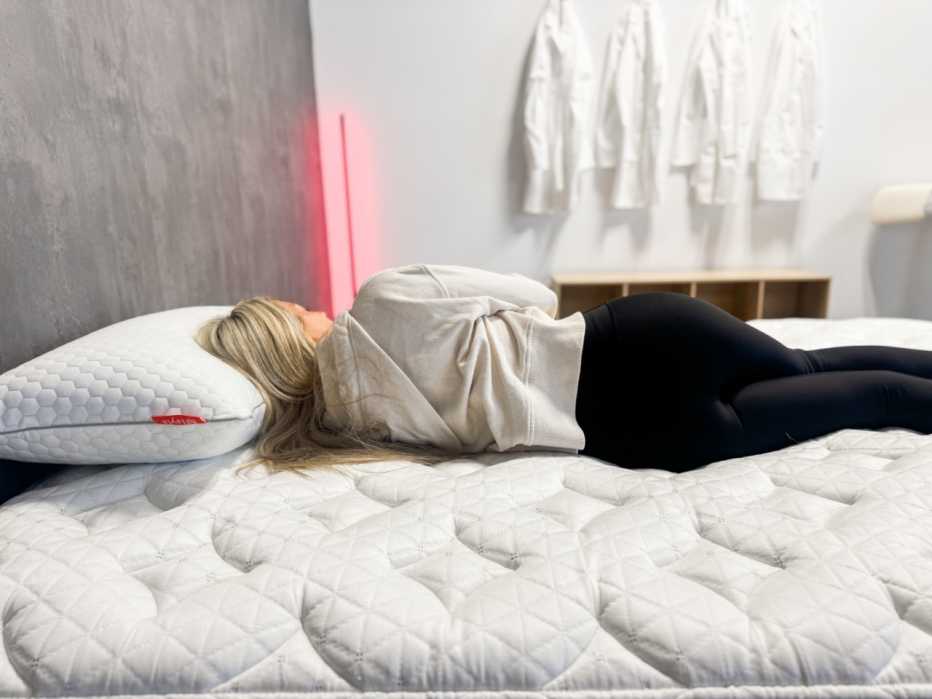 A woman lying on her side on the Helix Midnight mattress.