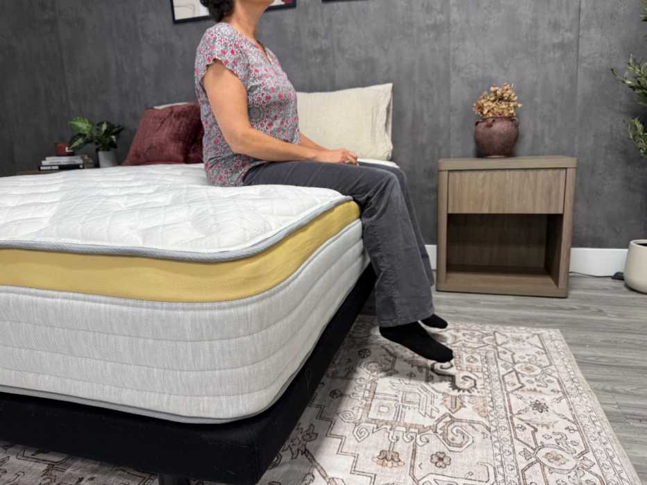 Woman sitting on the edge of the Helix Dawn mattress.
