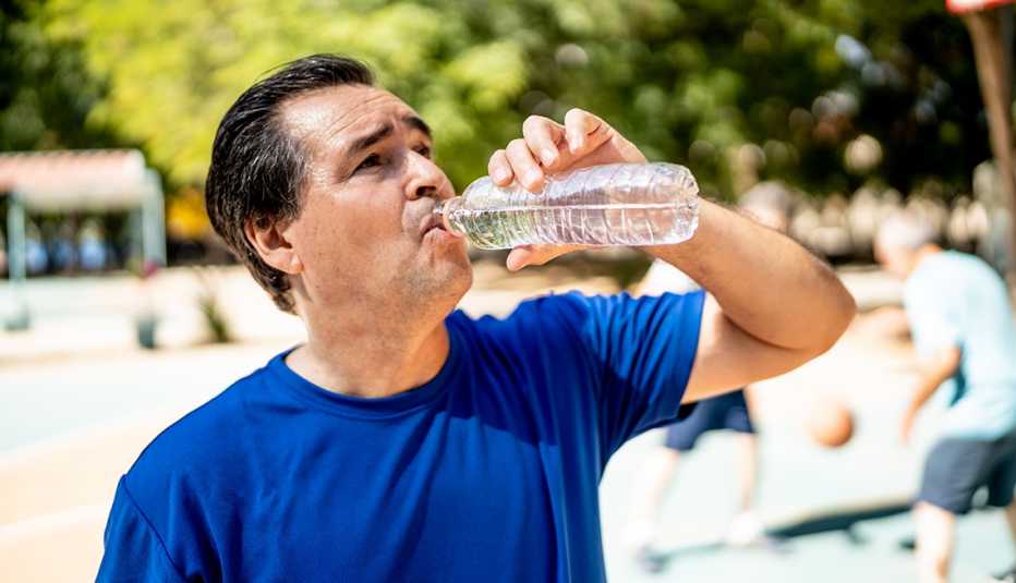 Mature man drinking water at the basketball court