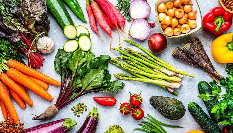 overhead view of raw organic vegetables whole and chopped on a kitchen counter