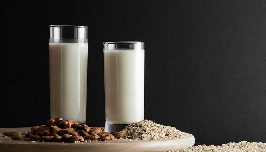 a glass of almond milk next to a glass of oat milk