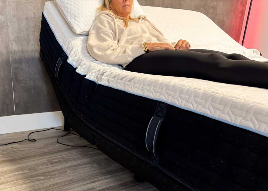 A woman sitting on the Nectar Classic Hybrid mattress while it’s on an adjustable base.
