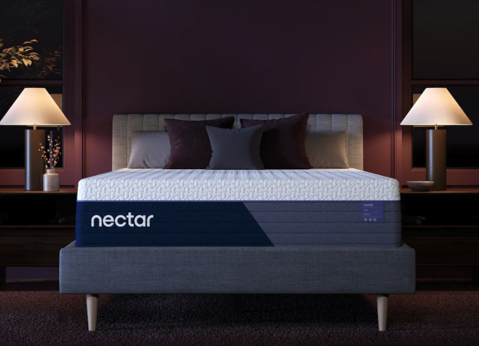 The Nectar Luxe Hybrid mattress in a dim bedroom with two lamps on.
