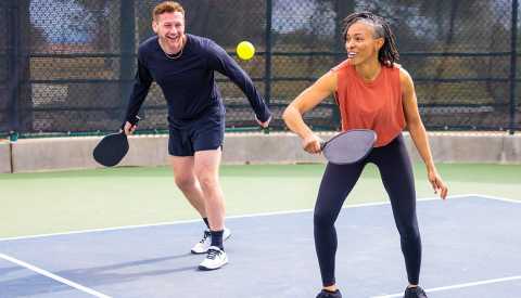 a man and a woman are smiling while playing pickleball a man and a woman are smiling while playing pickleball