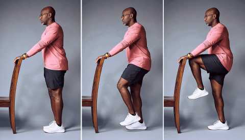 Personal trainer Archie Israel demonstrating a one legged balance move while supporting himself on a chair one legged balance exercise holding on to a chair for support