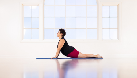 karen sanzo in cobra pose on mat; front side of body on mat, hands pushing upper body up, so back is curved