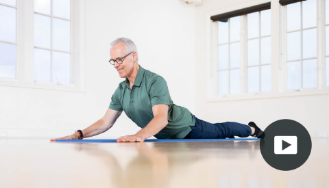 tom mccook in sphinx pose on mat; play button in bottom right corner