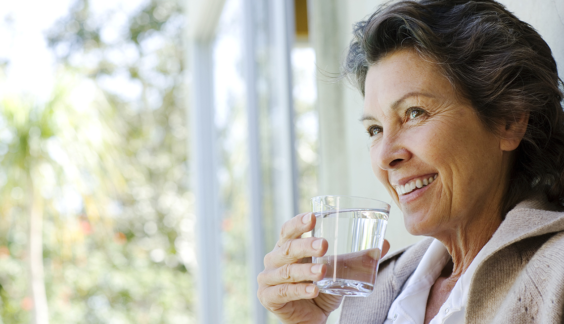 woman drinking a glass of water in the doorway