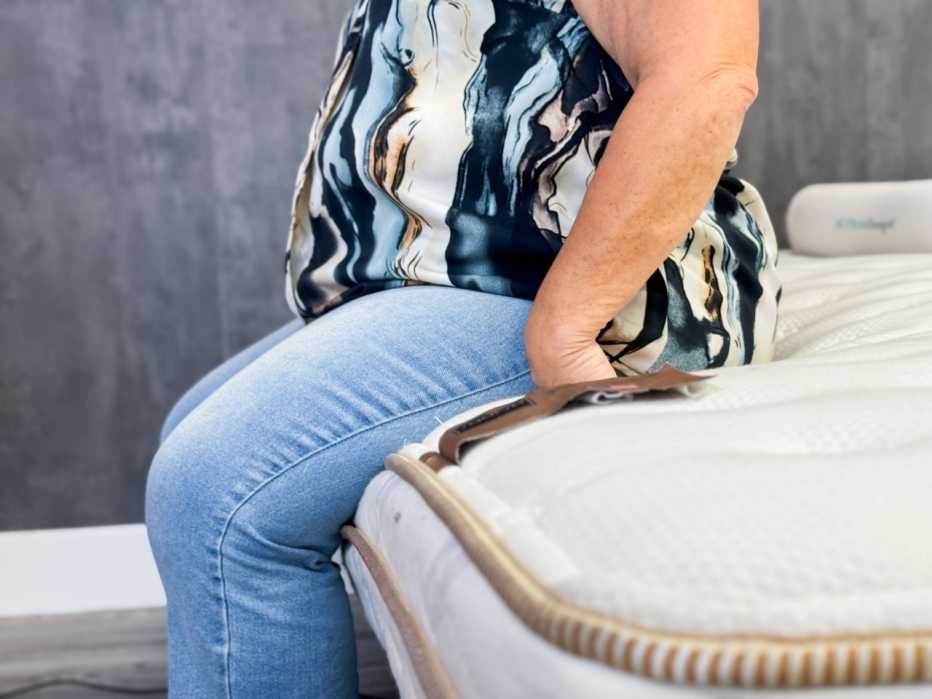 A woman sitting on the edge of the Saatva Classic mattress.