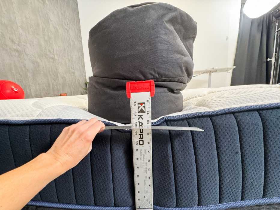 Testing the edge support of the DreamCloud Classic mattress with a 150-pound sandbag.
