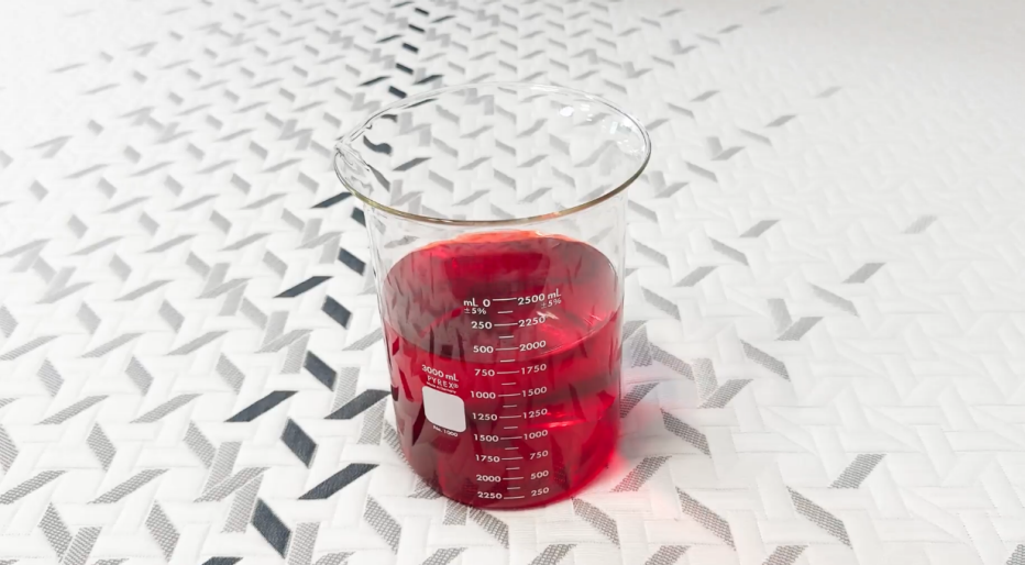 A glass of red liquid on the Nectar Luxe mattress. 
