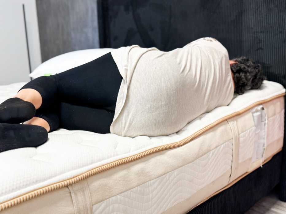 A woman lying on her side on the Saatva Rx mattress.
