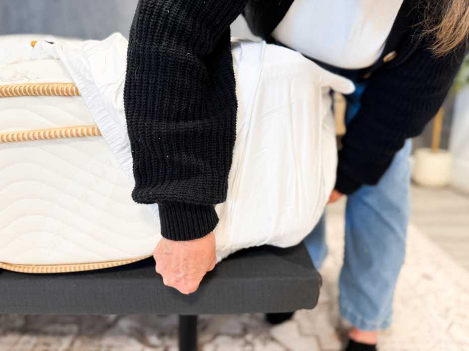 A woman putting the fitted Luxome Luxury Sheet on a mattress.
