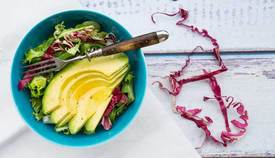 Bowl of leaf salad with sliced avocado
