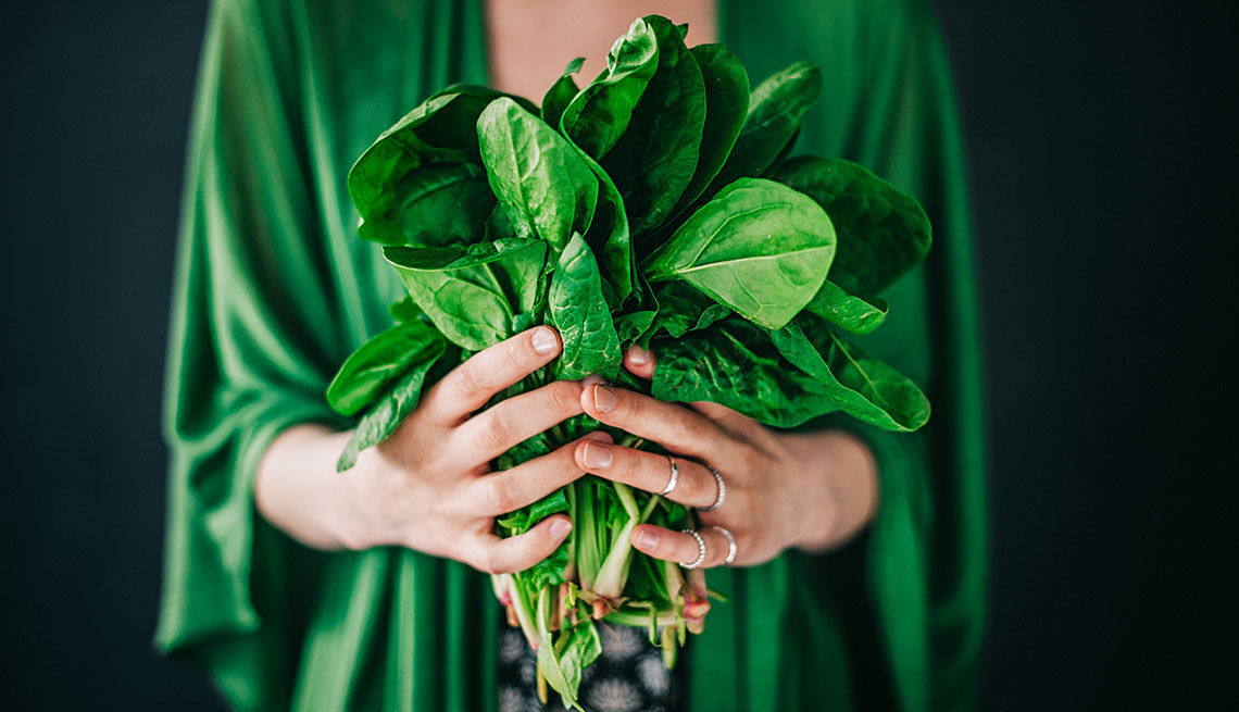 Young woman holding spinach leafs salad