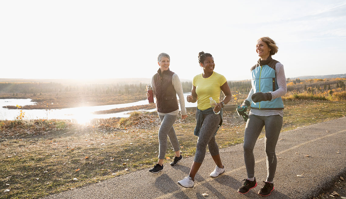 Women power walking exercising on sunny path in autumn park
