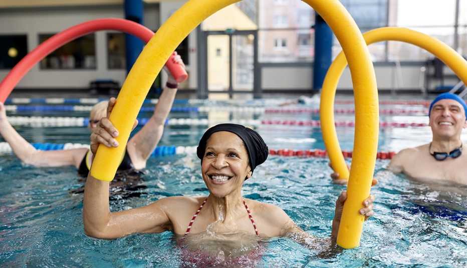woman doing swim noodle exercises in aerobics pool class people doing workout in swimming pool holding swim noodles
