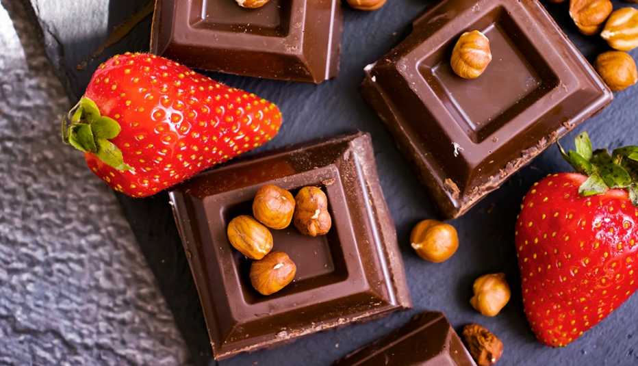 Dark chocolate, fresh strawberries, nuts on a dark background