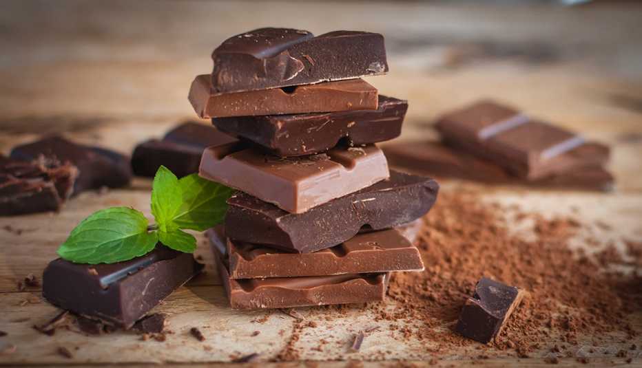 pieces broken off of a few different kinds of chocolate bars stacked on a table