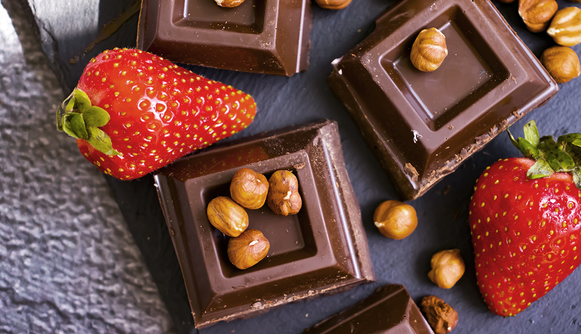 Dark chocolate, fresh strawberries, nuts on a dark background