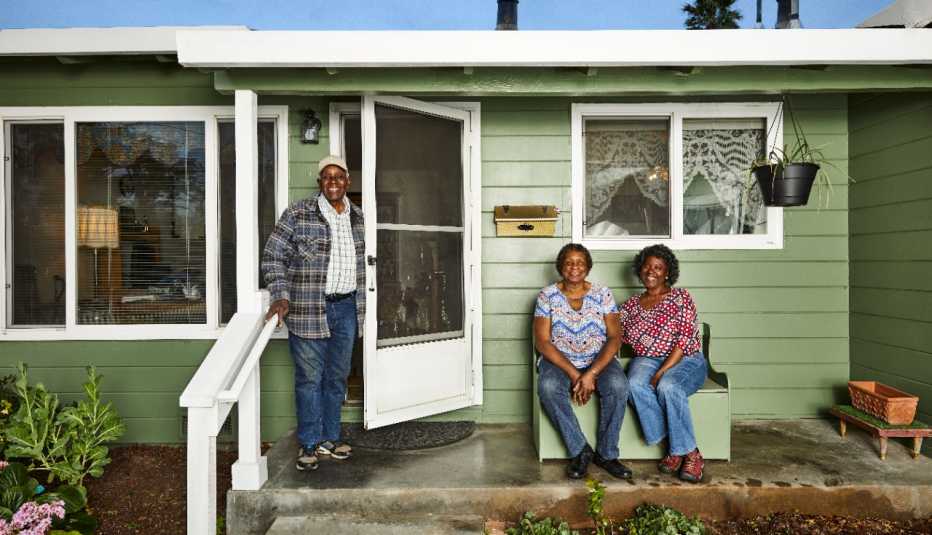 a smiling family on the porch of a green one level home