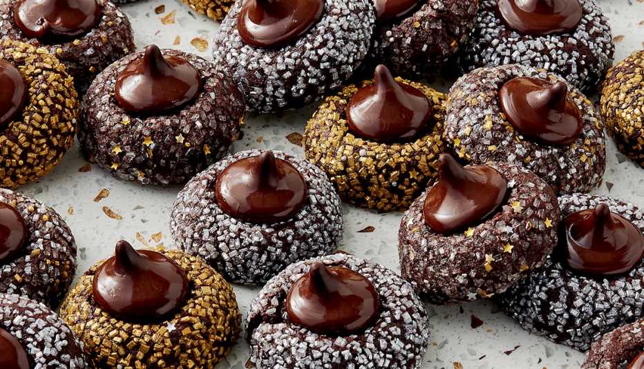 dark chocolate cookies with hershey's kisses on top; some cookies coated in silver sprinkles and some in gold