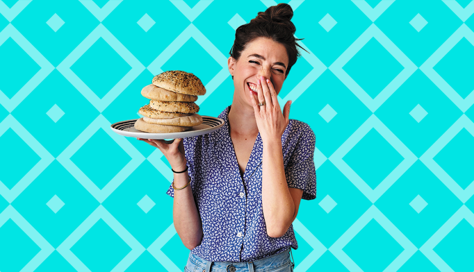 natasha feldman holding plate with stack of food on it; blue background with diamond shapes on it