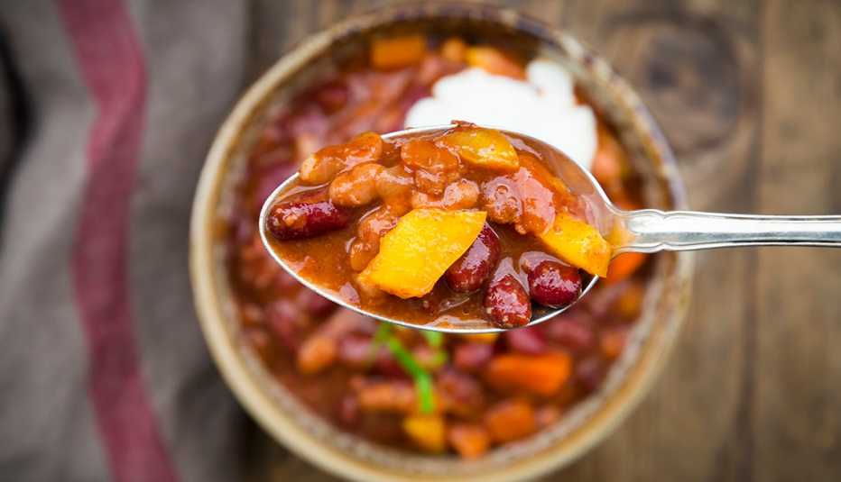 Chili con Carne with coriander and sour cream, spoon, close-up