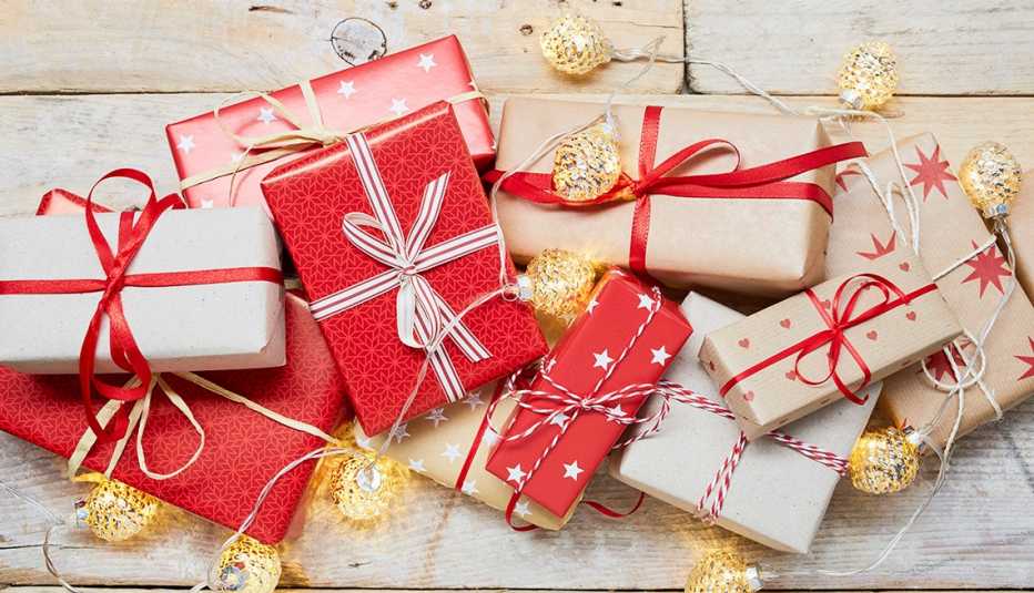 High angle view of a lot of wrapped Christmas gifts and strings lights on wooden background