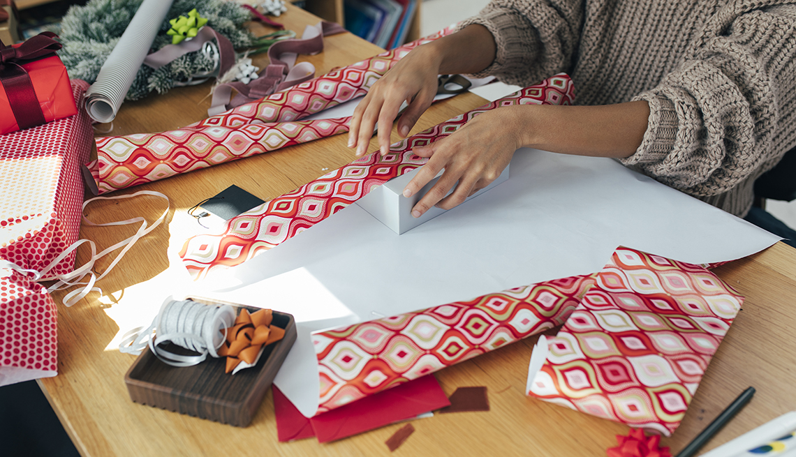 woman wrapping gifts with christmas themed wrapping paper