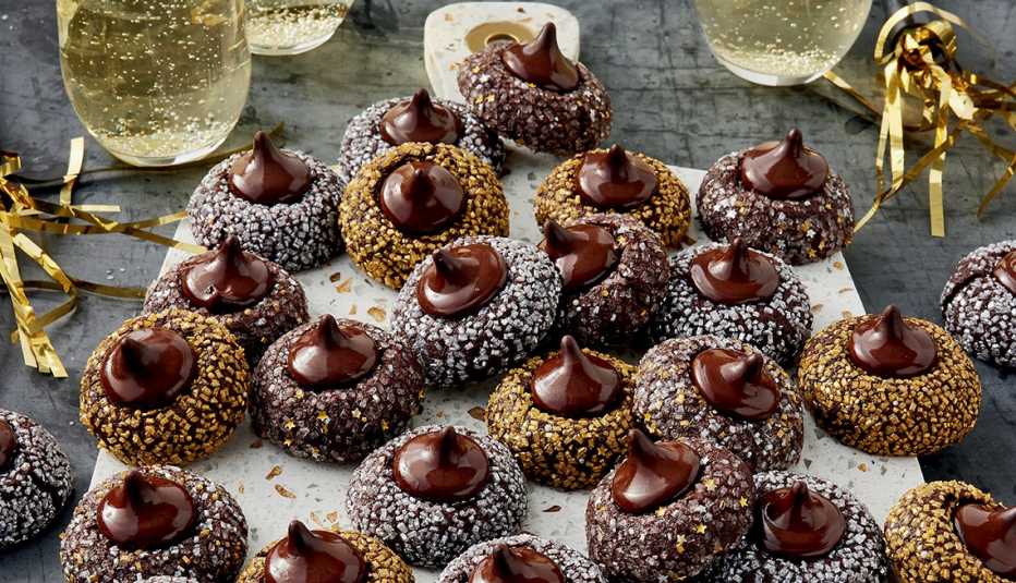 dark chocolate cookies with hershey's kisses on top; some cookies coated in silver sprinkles and some in gold