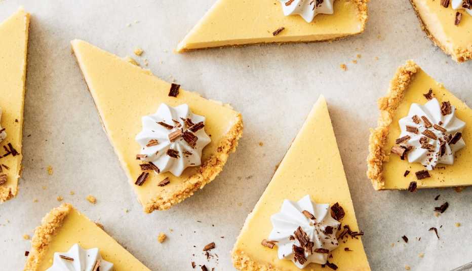 cheesecake pie slices with dollop of whipped cream and a sprinkle of chocolate shavings on each one