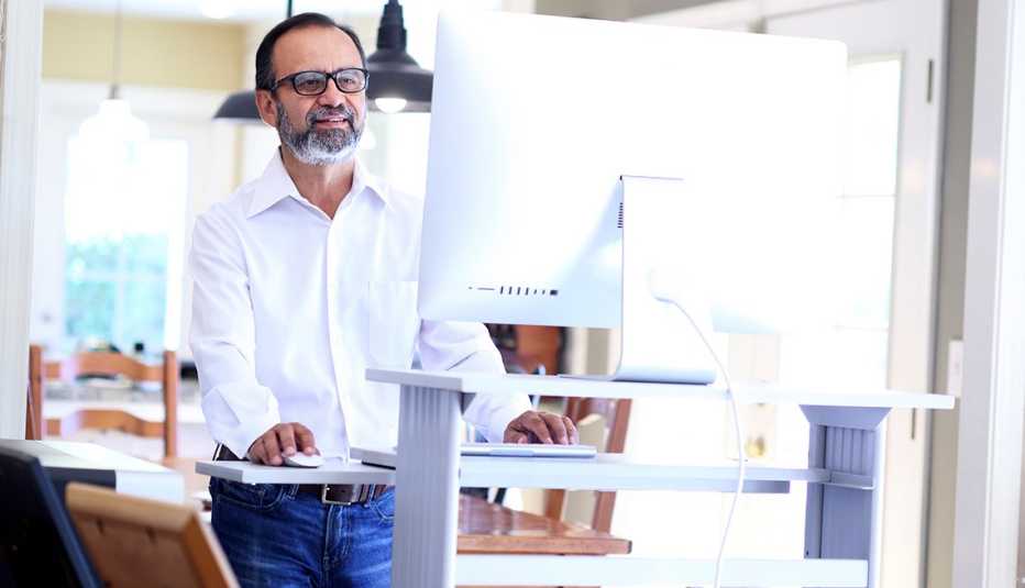 A businessman working at home stands at his standing desk 