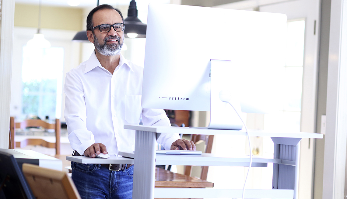 A businessman working at home stands at his standing desk 