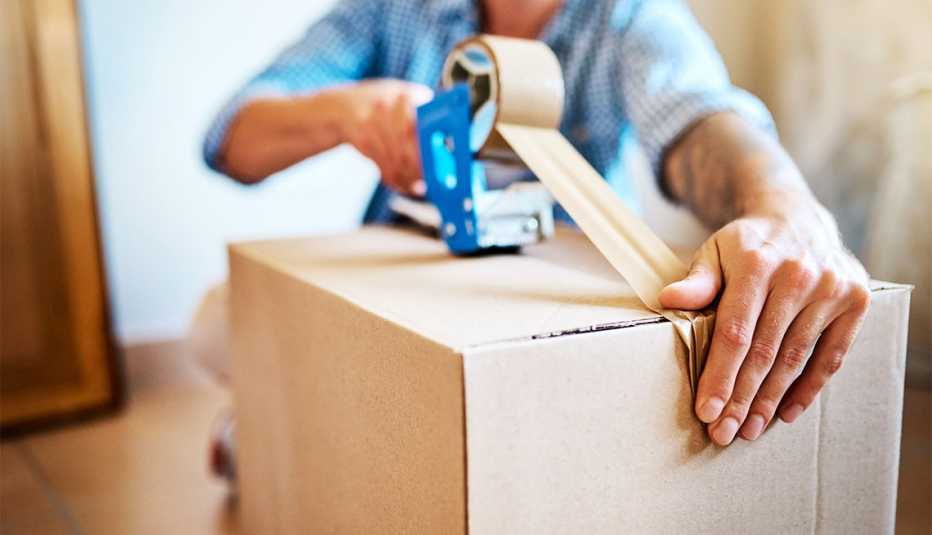 a person taping up a box with packing tape