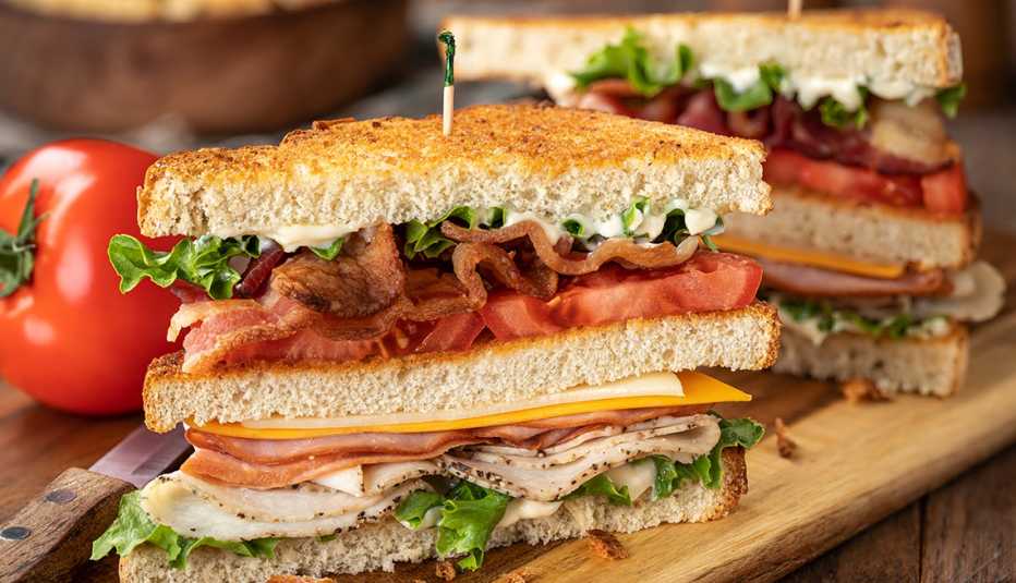 a club sandwich sliced in half on a wooden tray