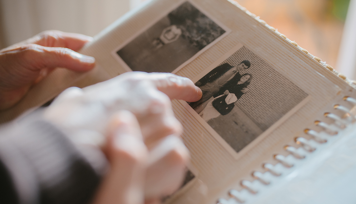 Close up view of a grandmother sharing memories and stories with her granddaughter while showing her an old family photo album. Memories and family concept.