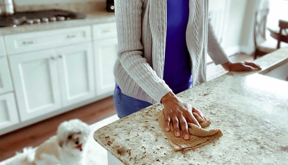 woman wipes down kitchen counter while out-of-focus dog yawns behind her