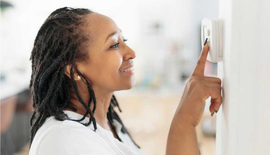 a lady adjusting the climate control panel on the wall wall thermostat