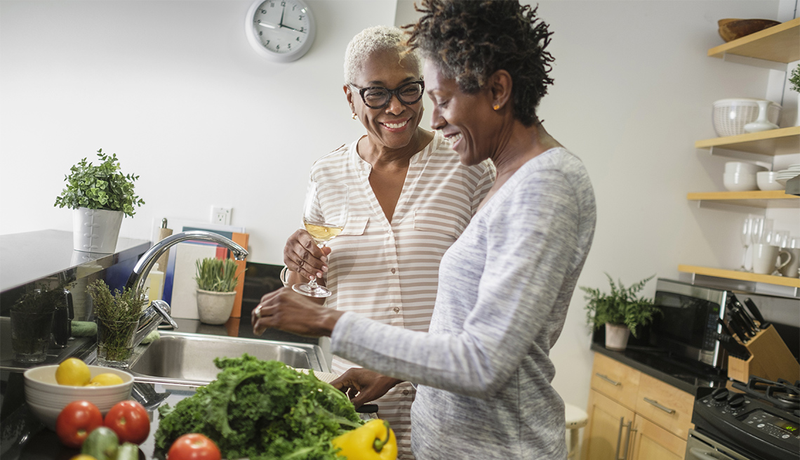 two women smiling in a kitchen, preparing a meal