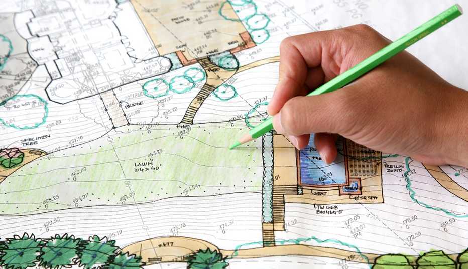 a hand holding a pencil drawing on a blueprint